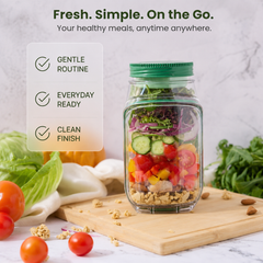 Portable salad jar with green twist lid filled with fresh mixed salad on a marble counter